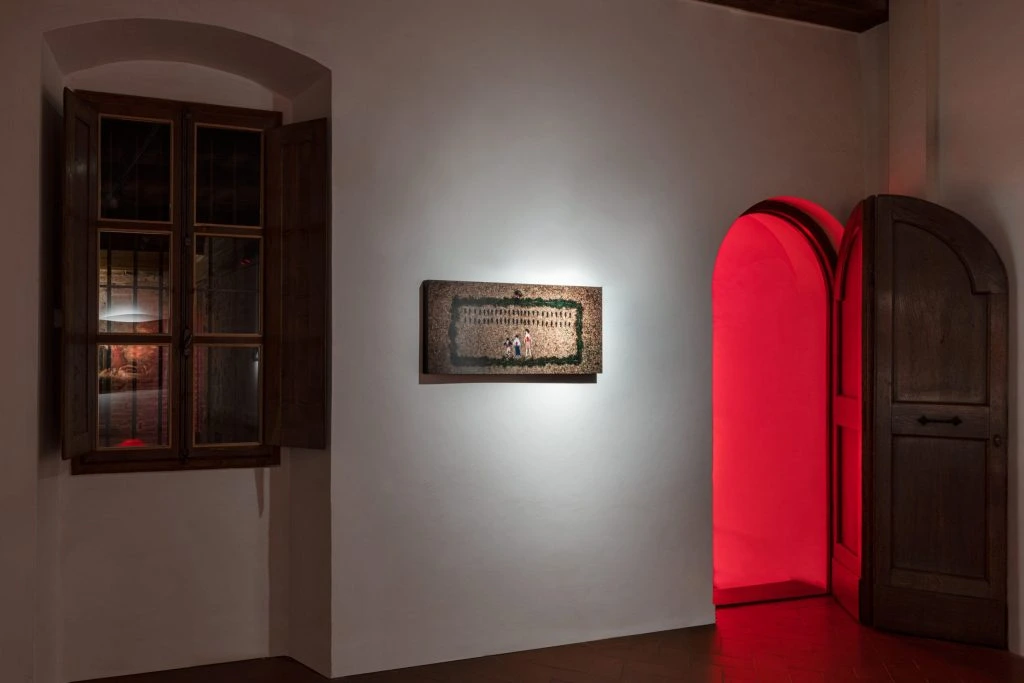 A photographic work beside a doorway illuminated in red.