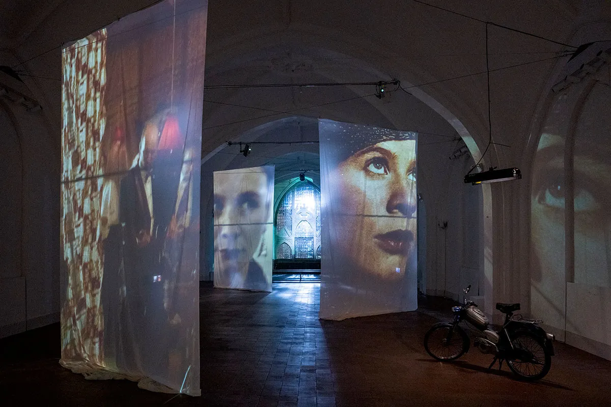 Film projections suspended within the vaulted church interior at Nikolaj Kunsthal